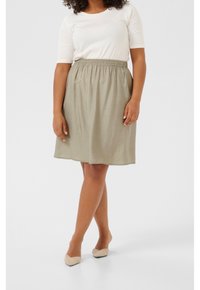 Une jupe olive jusqu'aux genoux en tissu léger avec une taille élastique, assortie à un t-shirt blanc ajusté.