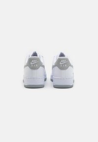 Hvide Nike Air sneakers med grå accenter. Glat læderoverdel, let polstret krave, gummisål med struktureret greb og logo-detaljer.