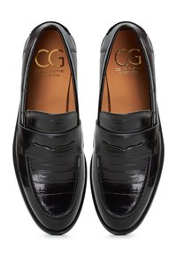 Svarta läderloafers med en glänsande yta, utrustade med ett band över vaden och subtila sömdetaljer. Inuti märkt med "CG."
