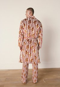 Set di accappatoio e pantaloni a righe rosse e bianche con stampe di omini di pan di zenzero. Tessuto morbido con cintura da annodare e maniche lunghe.
