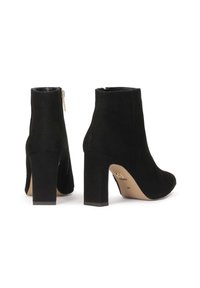 Bottes cheville en daim noir avec talons carrés et fermetures éclair latérales, vues de dos et de côté sur un fond blanc.