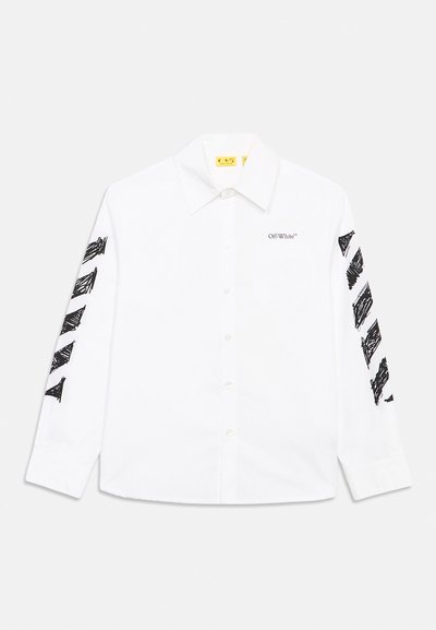 Λευκό πουκάμισο με μακριά μανίκια και κουμπιά, με μαύρα διαγώνια σχέδια σε στυλ γραφής στα μανίκια και μικρό κείμενο "Off-White™" στην περιοχή της τσέπης στο στήθος.