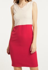 Robe sans manches avec un haut beige clair et un bas rouge, dotée d'un col en V et d'un design lisse et ajusté. Confectionnée en tissu doux.