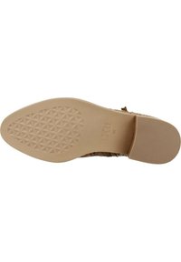 Suela de zapato plana color beige con un patrón de diamantes texturizado, que presenta un material suave y flexible, además de un leve tacón para mayor comodidad.