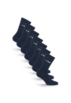 Sept paires de chaussettes noires crew avec un petit logo Fila blanc et rouge sur le côté, disposées en ligne diagonale sur fond blanc.