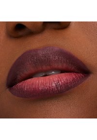 Lepper med en gradient fra dyp bær til myk rosa, med en matt finish og synlig tekstur, satt mot en glatt, mørkere hudtone.