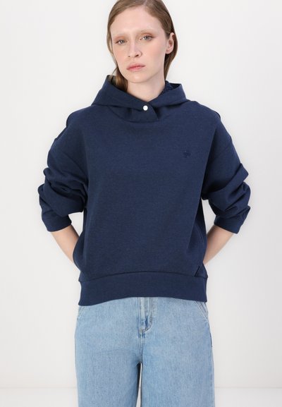 Sweat-shirt à capuche bleu marine en tissu doux, avec une coupe décontractée, des manches retroussées et un petit logo sur la poitrine.