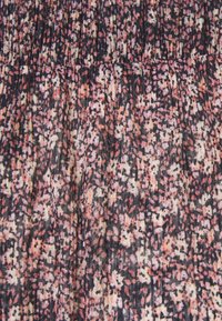 Un tissu à motif floral présente un mélange de teintes roses, noires et crème, avec une apparence texturée et légèrement froissée.