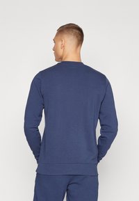 Donkerblauwe sweatshirt met lange mouwen, ronde halslijn, ribgebreide manchetten en tailleband, gemaakt van een zachte, gestructureerde stof.