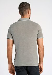 Harmaa polo-paita, jossa on teksturoitu kangas ja kontrastivärit valkoisella ja vihreällä kauluskoristeella. Lyhyet hihat ja suora helman muoto.