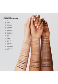 Långvariga krämögonskugga swatches på tre armar. Olika hudtoner med horisontella ränder i nyanser från ljus till mörk, numrerade.