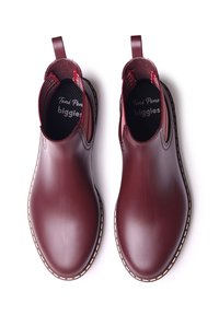 Bottes de cheville en caoutchouc bourgogne avec des panneaux latéraux élastiques, des tirants en boucle et des coutures contrastées le long de la semelle. Semelle intérieure texturée visible.