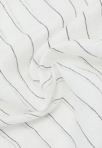 Tela blanca con finas y desiguales rayas negras. La textura parece ligera y ligeramente translúcida, con un acabado suave y tejido.