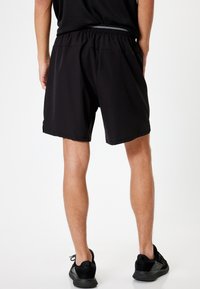 Sort athletic shorts med elastisk talje, glat tekstur og sidelommer. Har let buet kant for nem bevægelse.