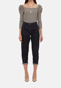 Pruhovaný černobílý top s dlouhým rukávem a nabíranými rameny, zkombinovaný s tmavě modrými slim jeans a béžovými lodičkami na vysokém podpatku.