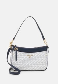 Crossbody taske med en hvid canvas krop, der har et gråt MK-logo mønster, marineblå læderdetaljer, guldbeslag og justerbar skulderrem.