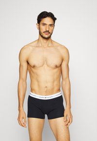 Crne bokserice s bijelim pojasom na kojem je logo "TOMMY HILFIGER". Glatka tkanina s udobnim krojem i minimalnim šavovima.