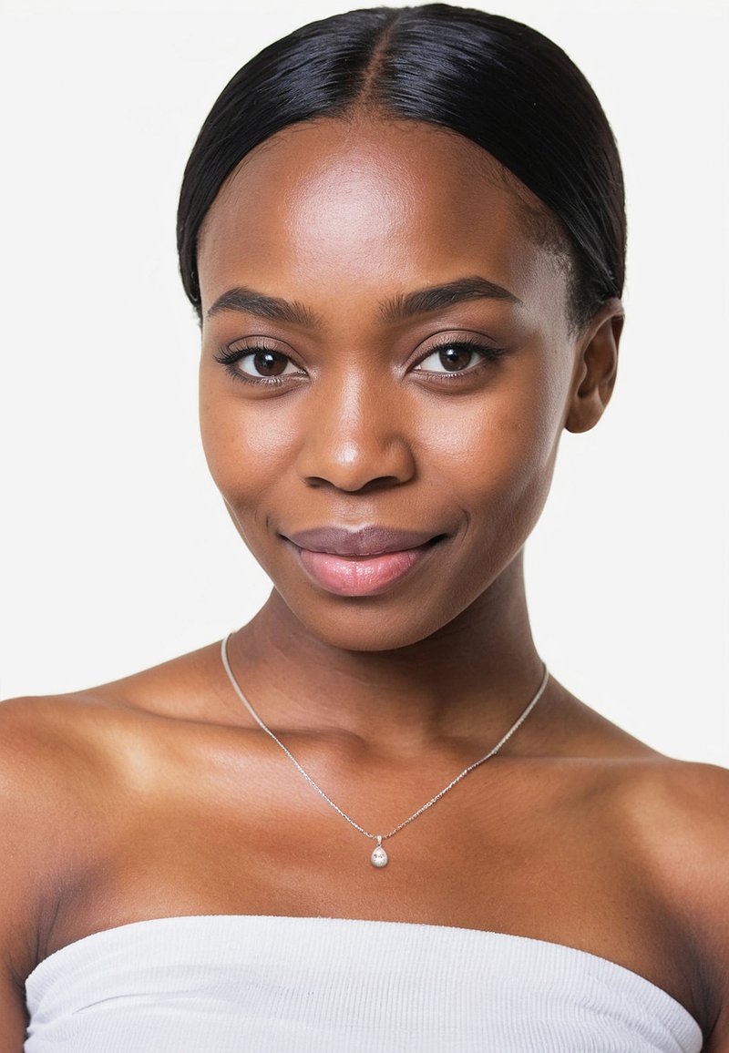 Silverhalsband med en liten tårformad hänge som bärs på bara axlar, mot en vit bakgrund, vilket framhäver designen och glansen.