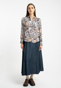 Koszula z długim rękawem w wielokolorowy wzór paisley, zestawiona z ciemnogranatową spódnicą maxi z dżinsu i brązowymi mokasynami. Gładka faktura materiału.