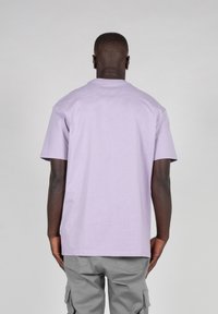 Tricou cu mânecă scurtă de culoare lavandă, din bumbac moale, cu un gât clasic rotund, având o tăietură lejeră și fără branding sau modele vizibile.