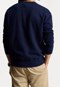 Marinblå sweatshirt med rund hals och långa ärmar. Har ribbad mudd och fåll, tillverkad av ett mjukt, strukturerat tyg.