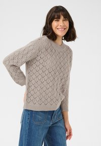 Maglione grigio chiaro lavorato a maglia con motivo a diamante in pizzo, colletto a girocollo a coste e maniche di lunghezza media, abbinato a jeans in denim blu.