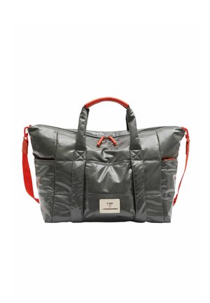 Sac de sport gris brillant avec poignées rouges, bandoulière rouge, poche avant, et une étiquette blanche avec texte noir sur le devant.