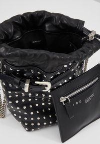 Svart läder bucket bag med silverstift, dragsko upptill, platt blixtlås ficka och kedjeaxelrem. "Tillverkad i Italien" etikett inuti.