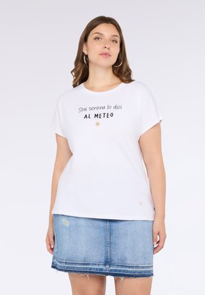 Witte T-shirt met korte mouwen met zwarte tekst "Stai serena lo dici AL METEO" en een zonafbeelding. Gecombineerd met een spijkerrok.