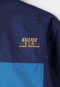 Camisa azul marino con textura de malla, que presenta una sección azul en la parte inferior y una impresión amarilla del logo "KILLTEC GLOBAL TRAVELLER".