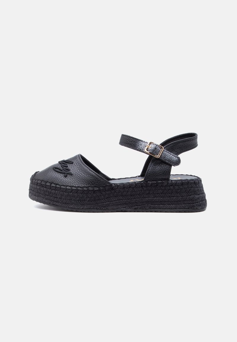 Sandale plate-forme noire texturée avec bride à la cheville et boucle dorée, bout fermé avec détail surpiqué à l'avant, semelle épaisse tissée.