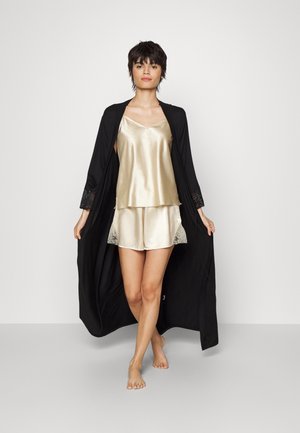 Schwarzer Gewand mit Spitzeneinsätzen an den Ärmeln über einem goldenen Satin-Camisole und passenden Shorts; glatte Textur, schichtetes Design und Spitzelemente an den Shorts.