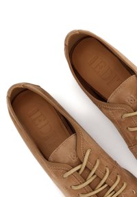 Rjave usnjene čevlje z okroglo nosom, teksturirano površino in bež vezalkami. Notranjost prikazuje vtisnjen logotip na gladki usnjeni podlogi.