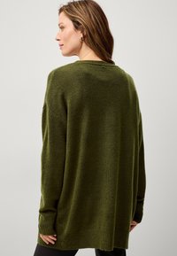 Maglione oversize di colore verde scuro, lavorato a maglia con finitura testurizzata, maniche ampie e orlo morbido, mostrato da dietro.