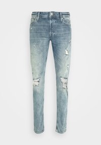 Ljust blå denimjeans med slim fit, som har slitna områden och rivdetaljer, mjuk textur och fransade fållar längst ner.