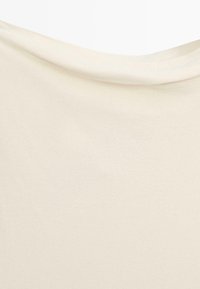 Tessuto morbido color crema con una texture liscia e un leggero drappeggio lungo il bordo superiore.