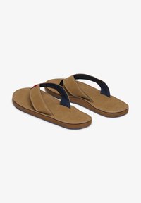 Chanclas de cuero marrón con tiras navy, que presentan una plantilla acolchada y una suela texturizada. Costuras decorativas a lo largo de los bordes.