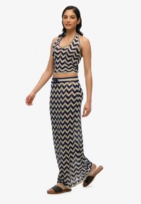 Halter-nakke top og lang nederdel sæt i marineblå og creme chevron mønster, med tekstureret stof og detalje med snørebånd i taljen.