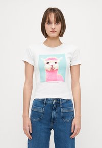 T-shirt en coton blanc avec un motif carré représentant un design coloré d'alpaca et du texte. Coupe décontractée avec des manches courtes et un col rond.
