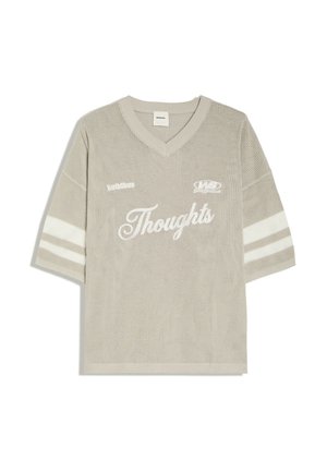 Beige strikket kortærmet sweater med V-udskæring, hvide striber på ærmerne og teksten "Thoughts" i stor skrift foran.