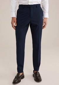 Jūras spēku stila bikses ar taisnu priekšpusi, jostas cilpām un vienu pogu. Gluds audums un šaurs piegriezums, kombinēts ar tumšiem mokasīniem.