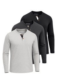 Tres camisetas henley de manga larga en gris claro, gris oscuro y negro. Cada una presenta un escote redondo con un detalle de botón. Material suave.