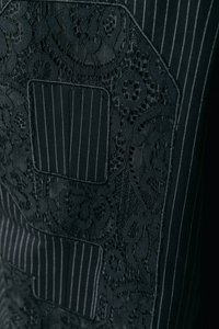 Μαύρο ύφασμα με συνδυασμό λεπτών ριγών και περίπλοκων δαντελένιων λεπτομερειών. Η υφή παρουσιάζει αντίθεση μεταξύ λείας και ανάγλυφων δαντελωτών σχεδίων.