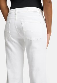 Jeans in denim bianco a vita alta, con cuciture sottili sulle tasche posteriori, etichetta rettangolare in vita e taglio dritto.