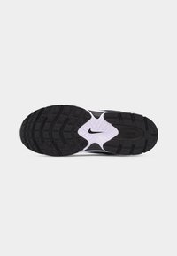 Μόνος μαυρόασπρου αθλητικού παπουτσιού Nike με υφή αντιολισθητικού μοτίβου και το κεντρικό λογότυπο Nike swoosh στη μέση της σόλας.