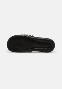 Black athletic shoe sole with ridged texture, featuring a curved design and prominent Nike logo. Smooth material with a slight gloss finish.
