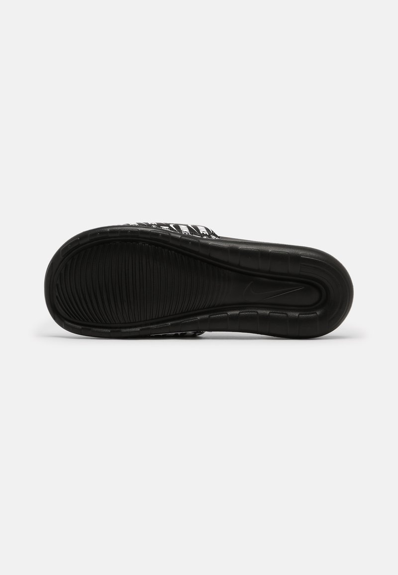 Suela de zapato deportivo negra con textura estriada, con un diseño curvado y un prominente logo de Nike. Material suave con un ligero acabado brillante.