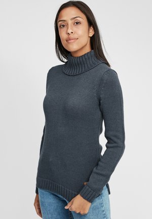 Maglione a collo alto grigio scuro con colletti e polsini a coste, design in maglia testurizzata e spacco laterale. Abbinato a jeans blu.