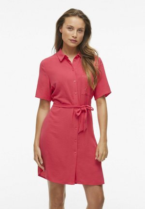 Koralinė mokasinų su trumpomis rankovėmis, prisiūta talija ir priekinė kišenė. Minkšta tekstūra, kasdienis dizainas, iki kelių ilgio.