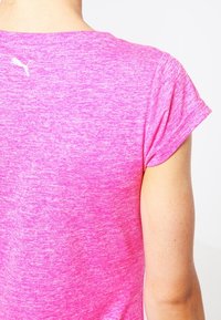 Kortärmad, atletisk T-shirt i ett livfullt rosa melerat tyg. Har en liten vit logotyp nära halsen. Slät textur, avslappnad passform.